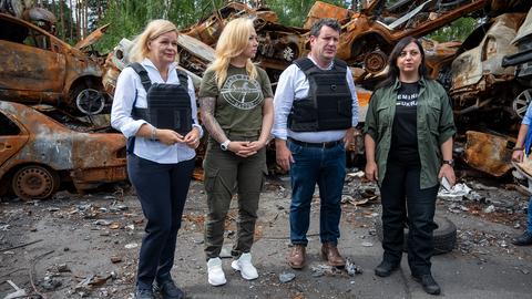 Nancy Faeser, Hubertus Heil, Mary Akopjan (r) und Anzhela Makeiewa (2.v.l), stehen vor zerstörten Autos in Irpin (Ukraine). (dpa)