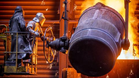 Arbeiter gießen flüssiges Eisen in der Eisengießerei Torgelow in vorbereitete Formen. (dpa)