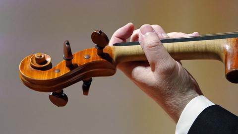 Hand eines Musikers eines Symphonieorchesters hält eine Geige (picture alliance/dpa)