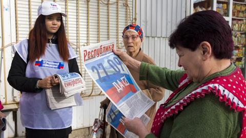 Ein Freiwilliger der regionalen Wahlkommission von Luhansk verteilt Zeitungen an die Bürger in Luhansk. (dpa)