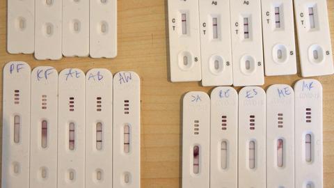 Positive und negative Corona-Selbsttests liegen nebeneinander auf einem Tisch. (dpa)