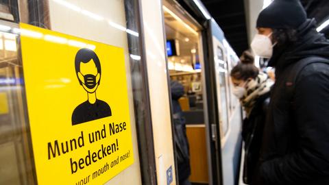 Ein Mann und eine Frau mit FFP2-Masken steigen in einer U-Bahnstation in die Bahn. (dpa)