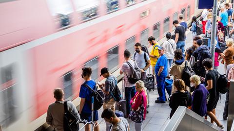 Fahrgäste am Bahnsteig, während ein Zug einfährt.  (dpa)