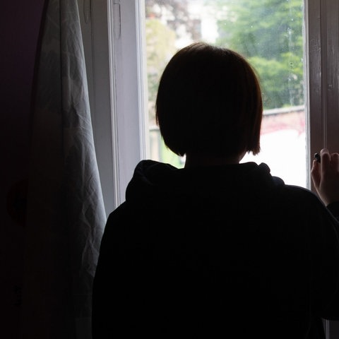  Eine Jugendliche blickt aus einem Fenster. (dpa)