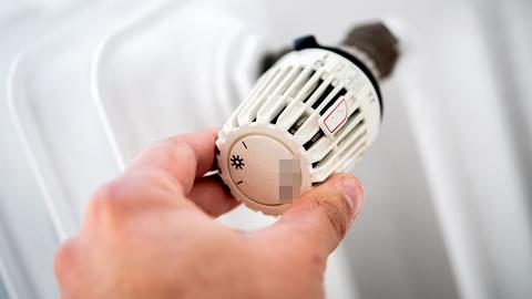 Ein Mann dreht in einer Wohnung am Thermostat einer Heizung. (dpa)