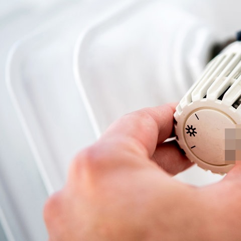 Ein Mann dreht in einer Wohnung am Thermostat einer Heizung. (dpa)