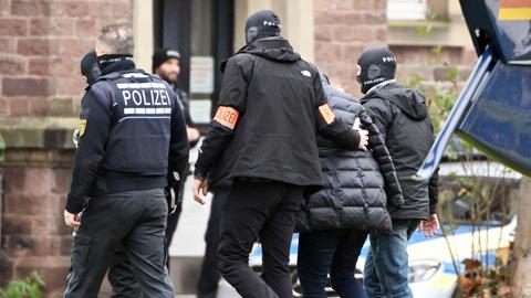 Polizisten führen nach einer Razzia im Reichsbürgermilieu eine Person zum Bundesgerichtshof in Karlsruhe (dpa)