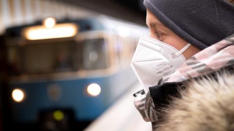 Eine Frau mit FFP2-Maske wartet an einem U-Bahnhof in München, während eine U-Bahn einfährt (Archivbild). (dpa)