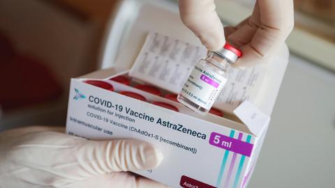 Eine Ampulle des Corona-Impfstoffs von AstraZeneca wird in einer Arztpraxis aus einer Packung entnommen. (dpa)