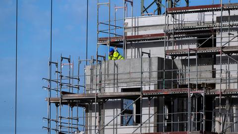 Ein Bauarbeiter steht auf einem Balkon auf einer Baustelle von einem neu gebauten Wohnhaus in Berlin. (picture alliance/dpa/Deutsche Pr)