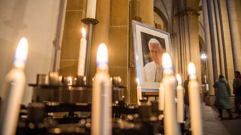 Ein Porträtbild vom emeritierten Papst Benedikt XVI. steht hinter Andachtskerzen im Paderborner Dom. (dpa)