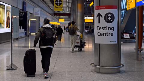 Ein Passagier geht nach seiner Ankunft in England an einem Schild in der Ankunftshalle von Terminal 5 am Londoner Flughafen Heathrow vorbei, das den Weg zu einem Corona-Testzentrum anzeigt. (dpa)