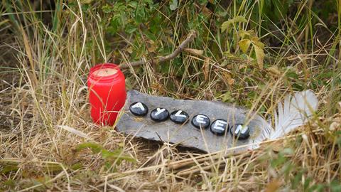 Eine Kerze und eine Tafel mit dem Namen Ayleen liegt am Ufer des Teufelsee im hessischen Wetteraukreis, in dem die Leiche der 14-jährigen Ayleen gefunden wurde. (dpa)