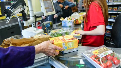 Eine Kundin nimmt in einem Supermarkt Waren vom Band an der Kasse. (dpa)
