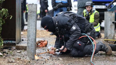 Ein Polizist entfernt mit einem Schweißgerät eine Barrikade in Lützerath (dpa)