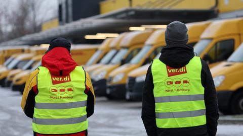 DHL-Mitarbeiter stehen vor Lastwagen und streiken. (dpa)