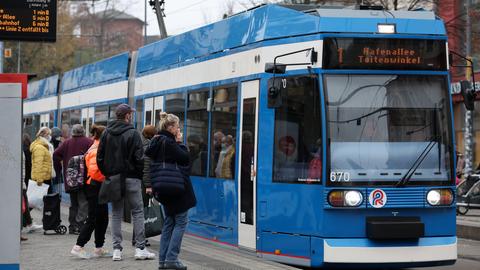Fahrgäste stehen in Rostock vor einer einfahrenden Straßenbahn. (dpa)