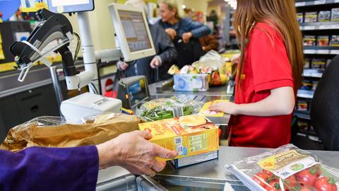 Eine Kundin nimmt in einem Berliner Supermarkt Waren vom Band an der Kasse, nachdem eine Kassiererin die Waren gescannt hat.  (dpa)