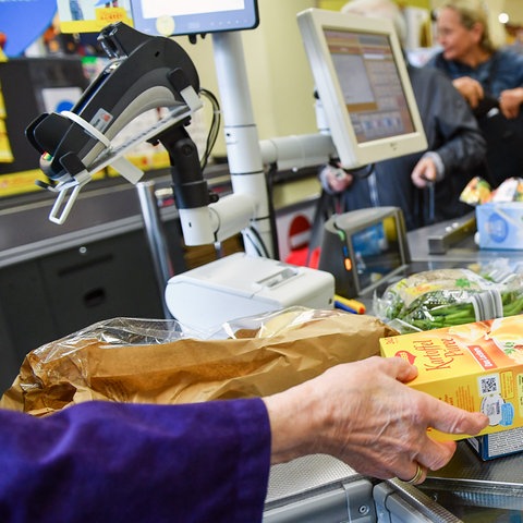 Eine Kundin nimmt in einem Berliner Supermarkt Waren vom Band an der Kasse, nachdem eine Kassiererin die Waren gescannt hat.  (dpa)