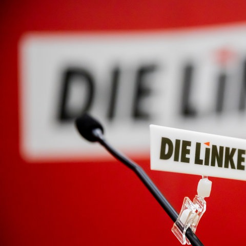 Logo der Partei Die Linke ist auf einem Schild an einem Mikrofon zu sehen (dpa)