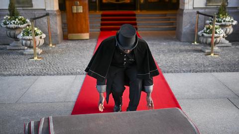 Doorman Timothy Uhunamure rollt vor dem Hotel Adlon in Berlin den roten Teppich aus.  (dpa)
