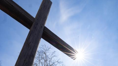 Ein christliches Kreuz mit Sonnenstrahlen (dpa)