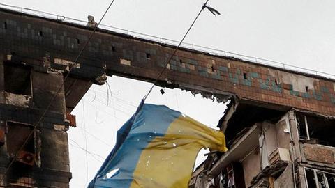 Eine zerrissene ukrainische Flagge hängt an einem Draht vor einem Wohnhaus, das während des ukrainisch-russischen Konflikts in der südlichen Hafenstadt Mariupol (Ukraine) am 14. April 2022 zerstört wurde.