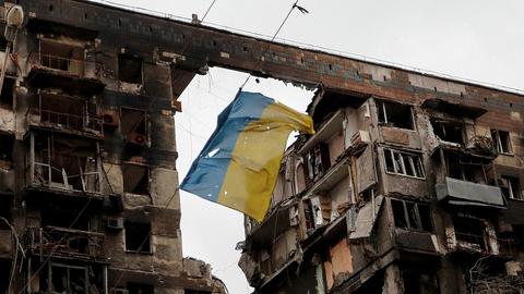 Eine zerrissene ukrainische Flagge hängt an einem Draht vor einem Wohnhaus, das während des ukrainisch-russischen Konflikts in der südlichen Hafenstadt Mariupol (Ukraine) am 14. April 2022 zerstört wurde.