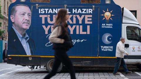 In Istanbuk (Türkei) geht eine Frau an einem Lkw mit Wahlwerbung für die AKP-Partei von Präsident Erdogan vorbei.