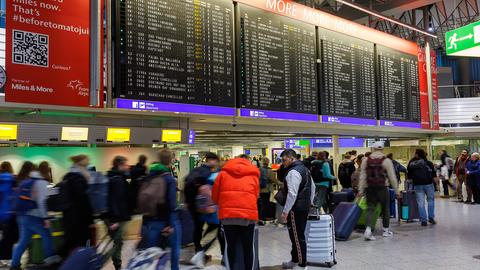 Passagiere stehen vor der Anzeigetafel im Terminal 1 am Frankfurter Flughafen.