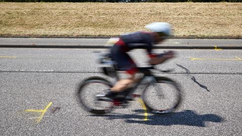 Triathleten fahren auf dem Rad an der Unglückstelle auf dem Deich vorbei.