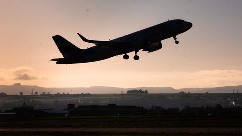 Ein Flugzeug startet am frühen Morgen im Sonnenaufgang.