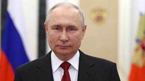 Wladimir Putin steht bei einer Fernsehansprache vor russischen Fahnen