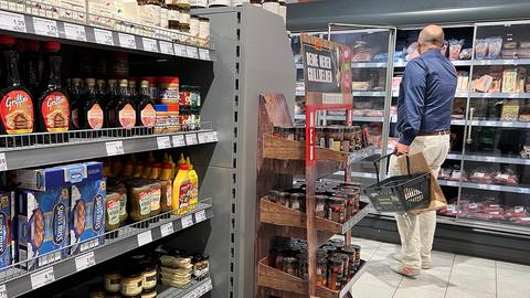 Ein Mann steht vor einem Kühlregal in einem Supermarkt.