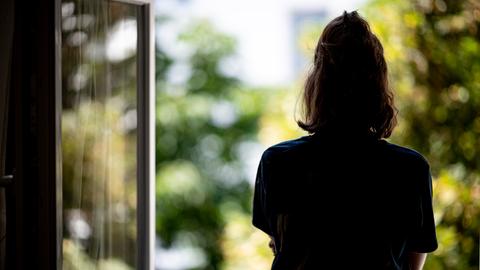 Ein Mädchen steht am Fenster und schaut raus.