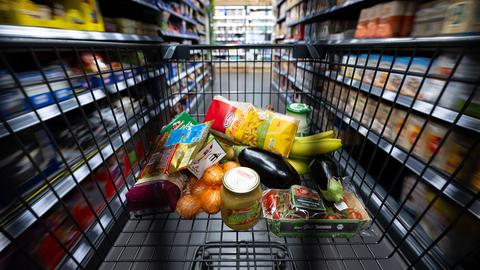 Verschiedene Lebensmittel liegen in einem Supermarkt in einem Einkaufswagen.