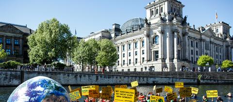 Aktivisten der Umweltschutzorganisation Greenpeace schwimmen am Reichstag in der Spree in Berlin. Mit der Aktion will die Organisation für mehr Klimaschutz demonstrieren. (dpa)