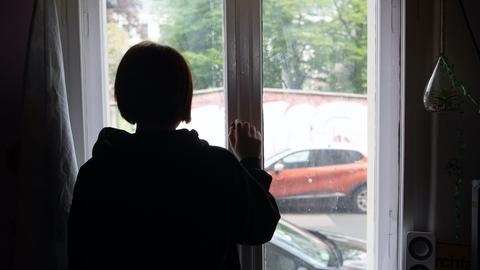 Eine Jugendliche blickt aus einem Fenster.