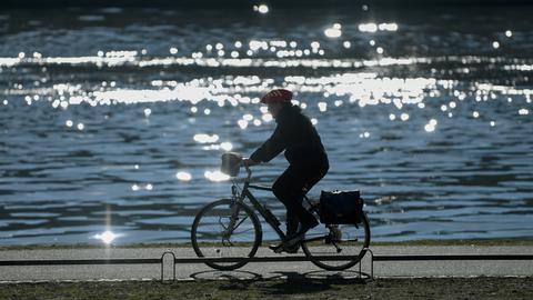  Ein Fahrradfahrer ist im morgendlichen Gegenlicht am Mainufer unterwegs.