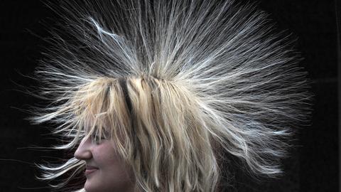 Frau testet in der Experimentalausstellung "Physik im Kaufpark" die elektrostatische Aufladung an ihren Haaren. 