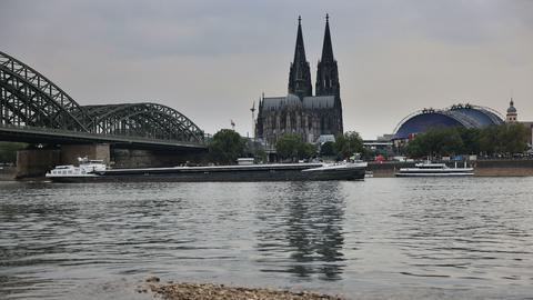 Ein Schiff fährt bei Niedrigwasser über den Rhein unter der Hohenzollernbrücke am Kölner Dom vorbei.
