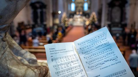 Menschen singen beim Pontifikalamt zu Weihnachten im Dom.