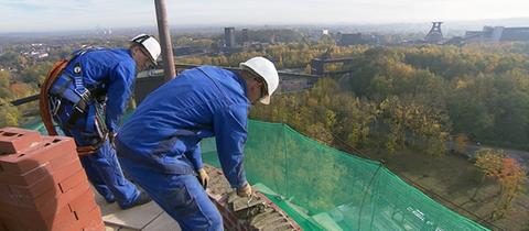 Männer arbeiten auf einem Schornstein