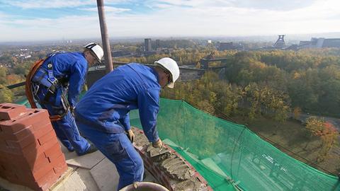 Männer arbeiten auf einem Schornstein