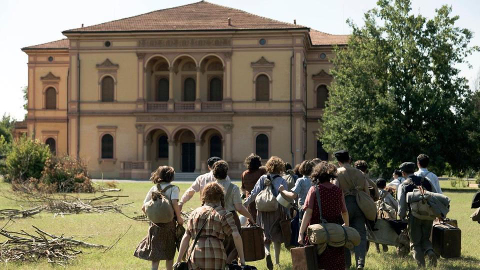 Kinder und Jugendliche laufen auf eine Villa zu.