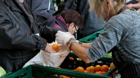 Ehrenamtliche Mitarbeiter der Tafeln verteilen an Nutzer der Einrichtung Lebensmittel.