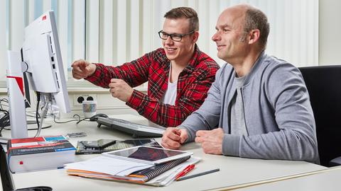 Auszubildender und Ausbilder besprechen sich am PC