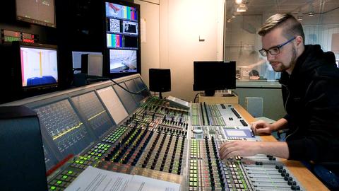 Auszubildender Mediengestalter sitzt im Studio am Mischpult