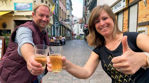 Tobias Kämmerer und Stadtführerin Verena Röse sind in Alt-Sachsenhausen und stoßen mit zwei Gläser Apfelwein an.