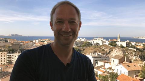 Tobias Kämmerer lächelt über den Dächern von Marseille in die Kamera.